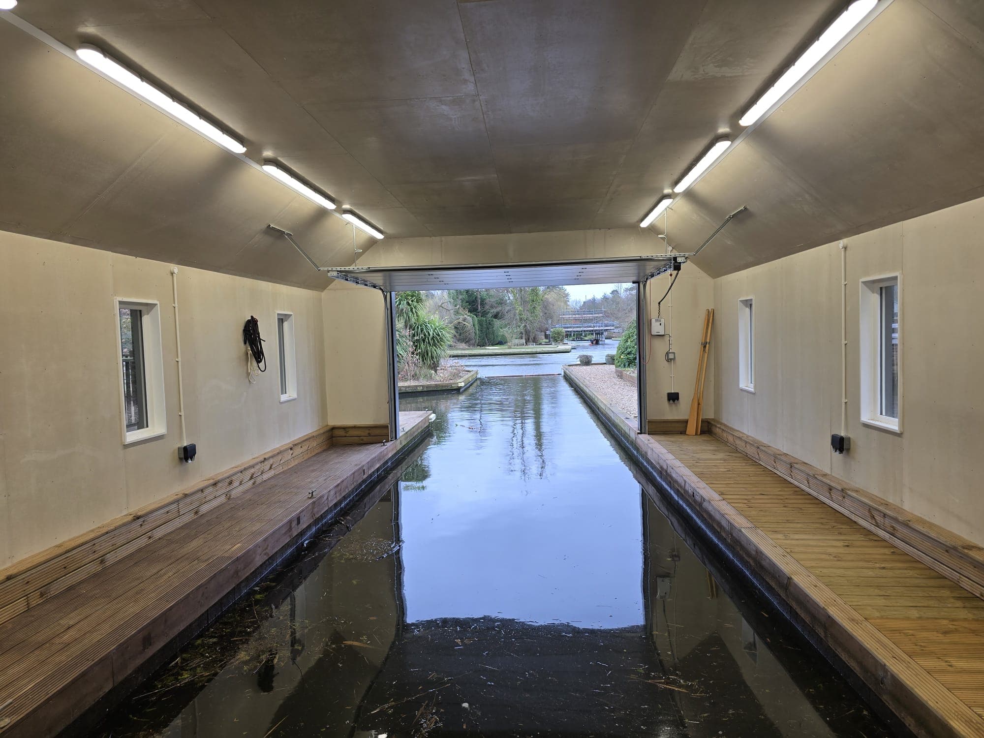 Interior view of a bespoke OGD boathouse installation with the sectional door open onto a canal